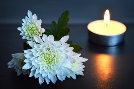 A picture of a flower next to a candle to illustrate grief.